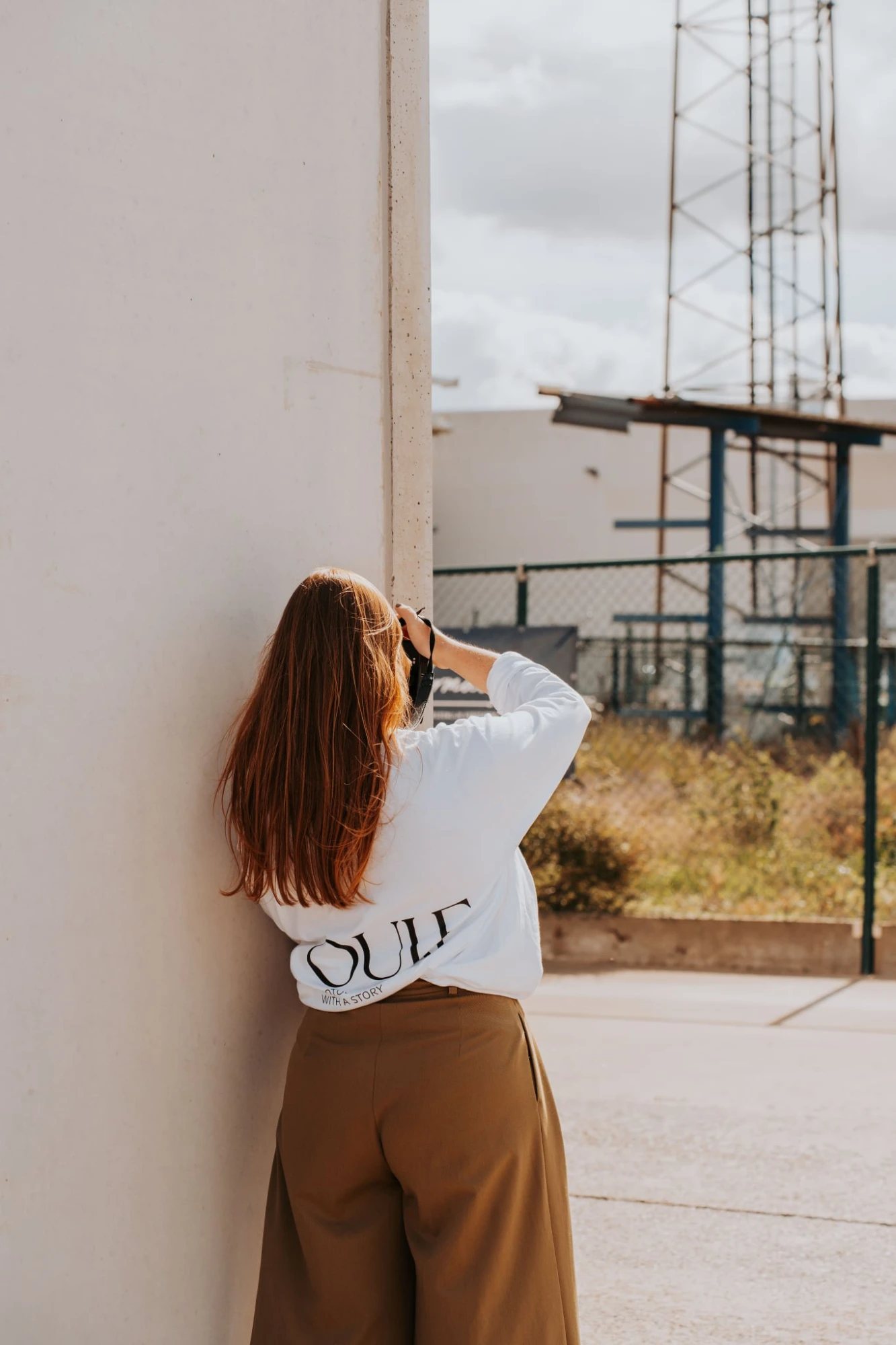 Louise fotografeert, op de rug gezien, in een trui met het OUI.E-logo