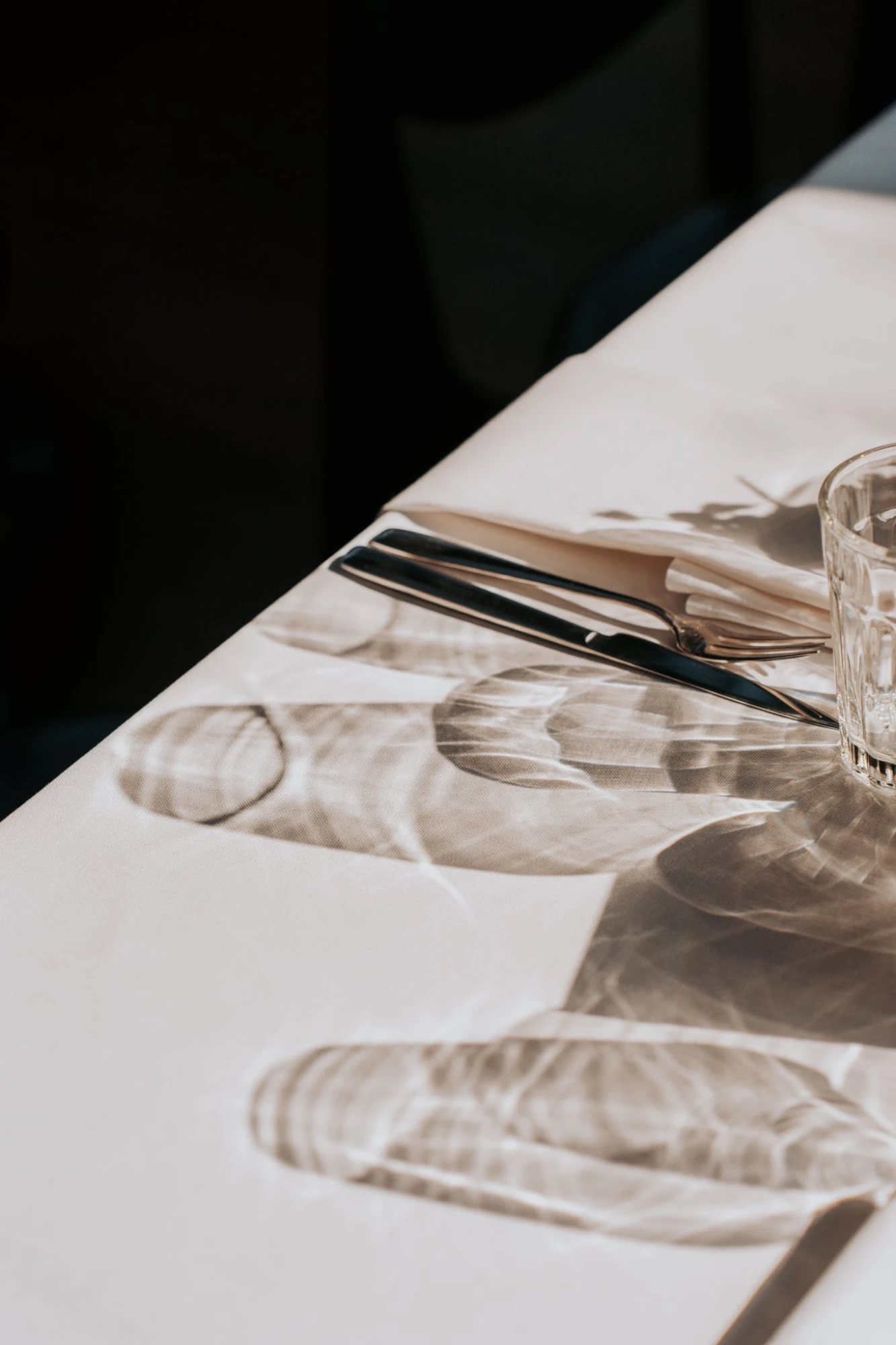 Bestek en een glas in het zonlicht op een gedekte tafel