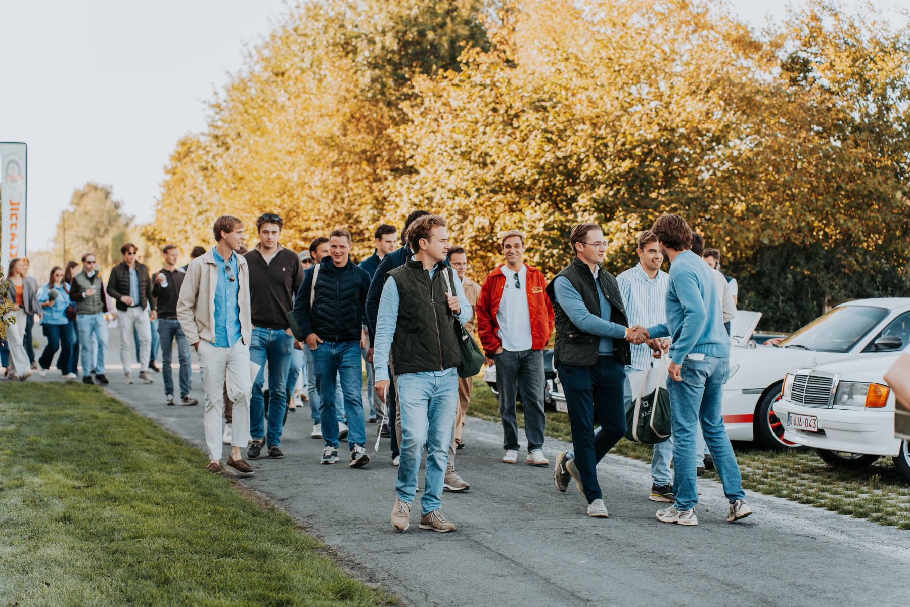 Groep wandelt langs geparkeerde oldtimers