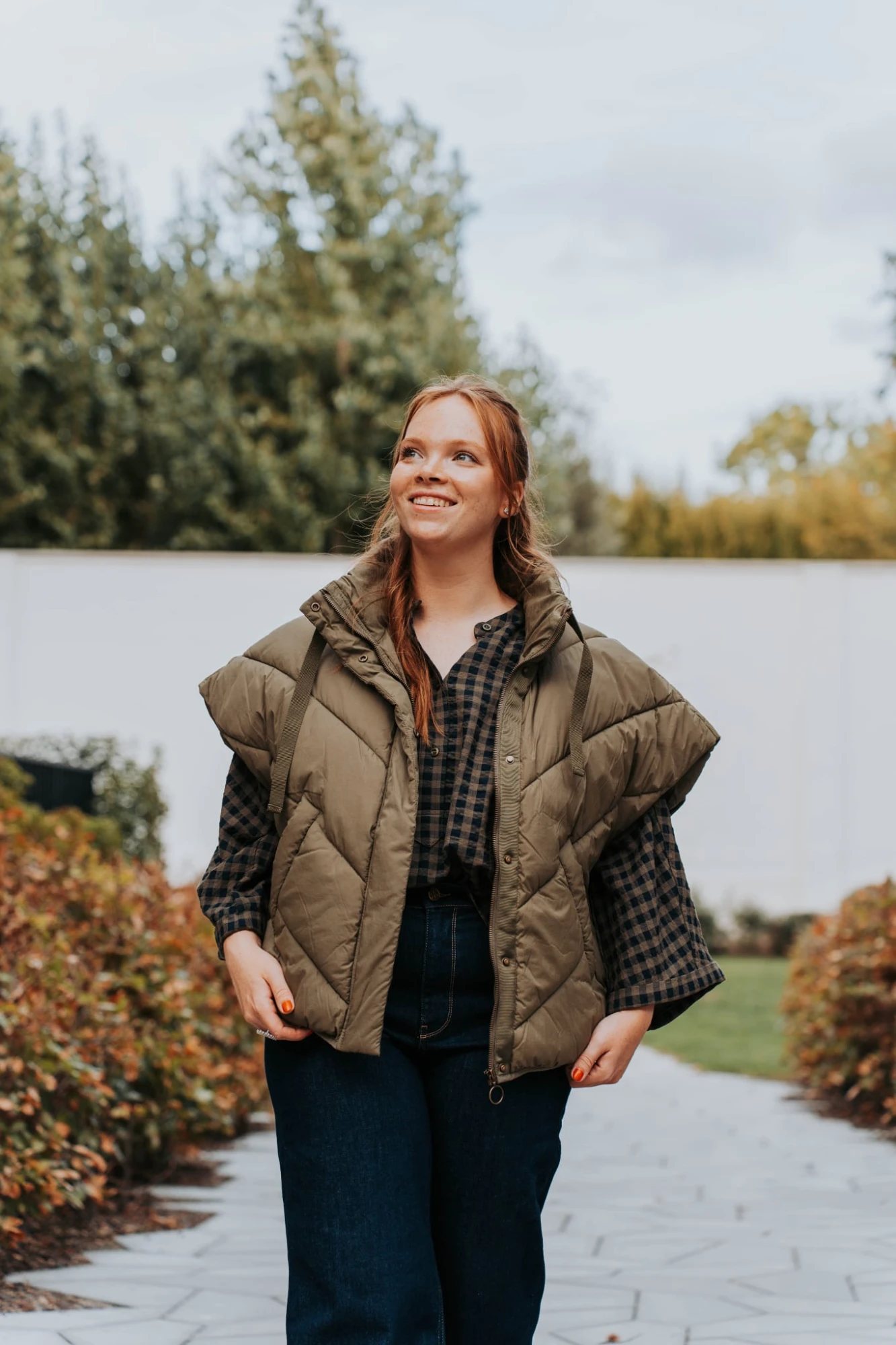 Lachende vrouw wandelt over een tuinpad