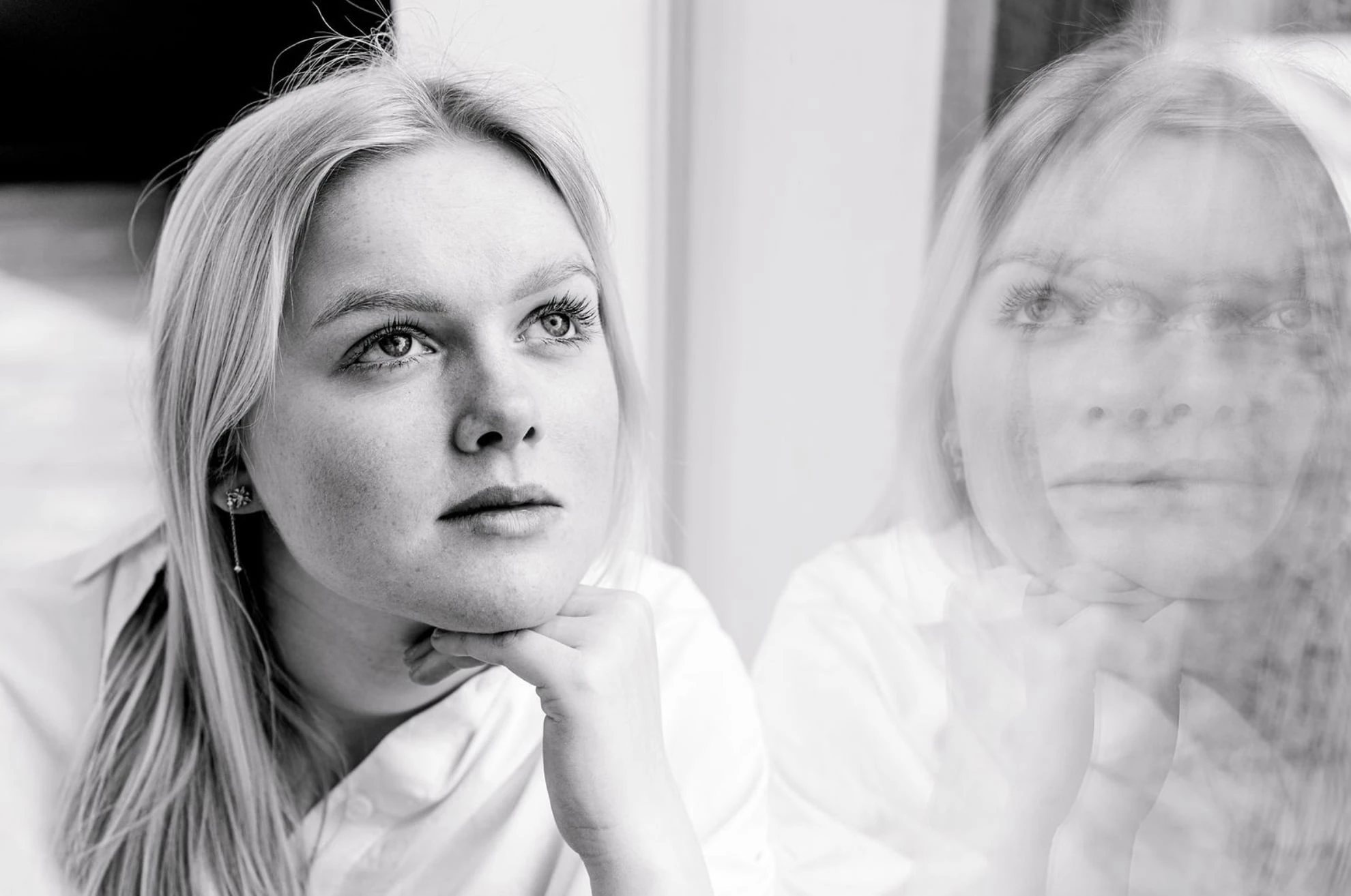 Zwart-wit portret van een vrouw die door een raam kijkt
